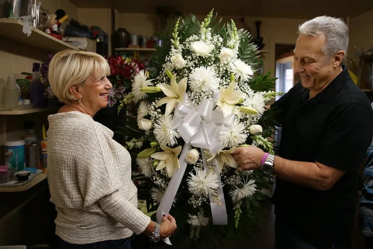 JoAnn Vacca, left, and her husband, John, right, with a flower arraignment at their shop, The Petal Pusher, in South Philadelphia. They have been selling flowers on South Broad for half a century, back to the time when the street, once lined with 14 funeral parlors, was known as "The Great Dark Way."