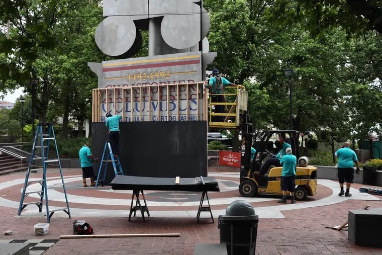 Delaware River Waterfront Corporation workers board up the bottom of the Christopher Columbus monument at Penn’s Landing in Philadelphia on Wednesday, June 17, 2020. The corporation, which maintains the monument, is covering up the bottom until the end of a public feedback process to determine whether it should be removed.