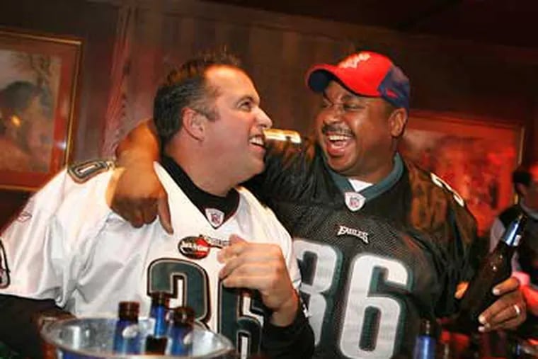 Paul Strickland (left) and Peter Graham are happy about an Eagles' score as they watch the Eagles-Vikings playoff game at the Fox and Hound in Center City. (Eric Mencher/Staff Photographer)