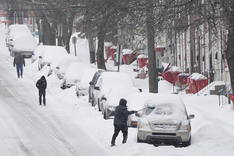 A man cleans the snow off his car in Norristown on February 18, 2021.