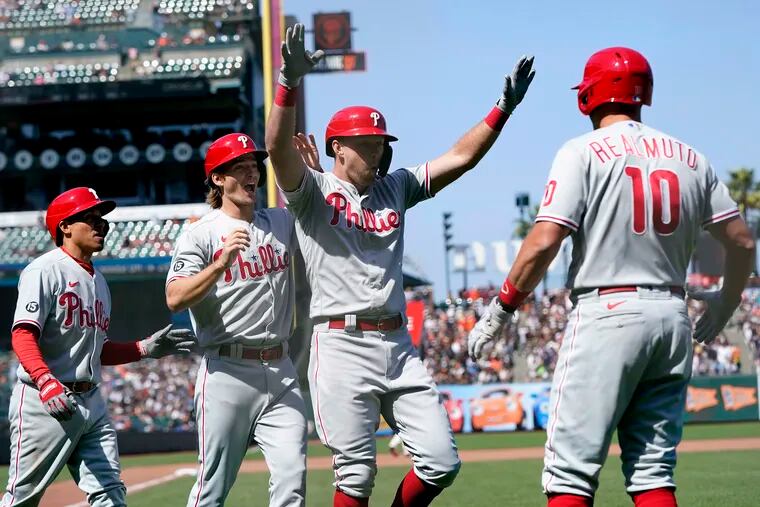The Phillies' Rhys Hoskins raises his arms after hitting a three-run home run that scored Ronald Torreyes (left) and Luke Williams during the seventh inning.