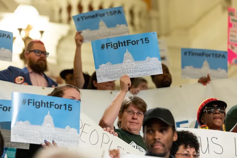 People hold up signs during a press conference and rally in 2019 calling for a $15 minimum wage.