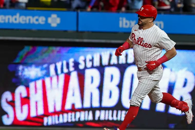 Kyle Schwarber rounds the bases in front of a Schwarbomb sign after a home run in the sixth inning of Game 2 of the baseball NLCS.