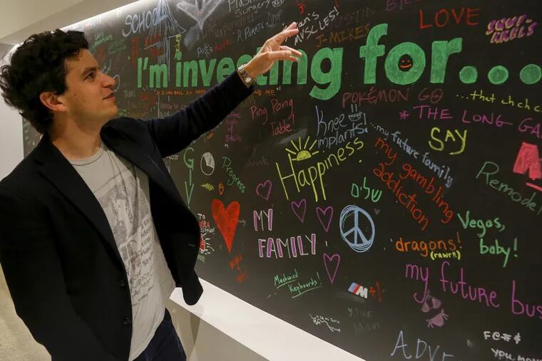 Noah Kerner, CEO of Acorns, looks at a wall in the Irvine, Calif., office where employees have written messages about their investment goals. Acorns is an investment company that is using behavioral economic theories to try to nudge its users to save more.