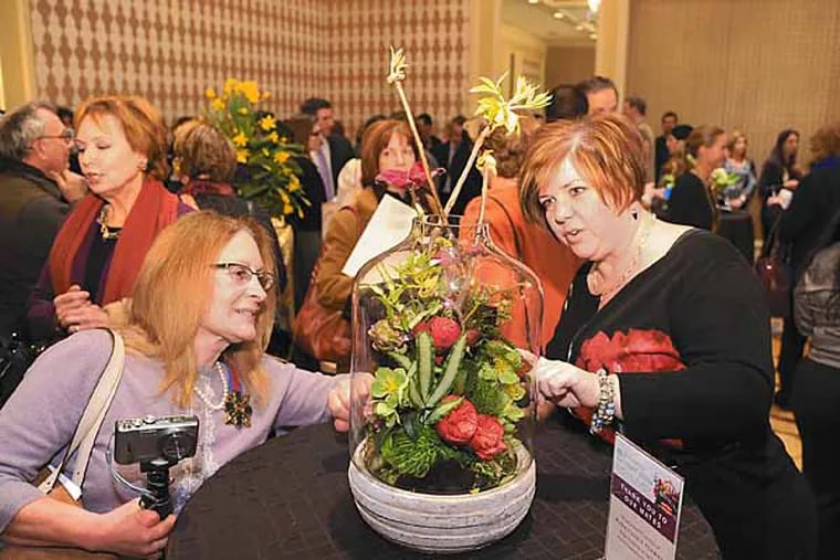 Flowers are blooming, at least for the Philadelphia Flower Show, as Gloria Day (left) of Pretty Dirty Ladies garden designs of Leesport, PA and Susan Cacioppo, manager of Heatherwood senior living community of Honey Brook, inspect a table centerpiece at The Four Seasons Hotel where a kickoff press conference was held for the Flower Show.  ( CLEM MURRAY / Staff Photographer )