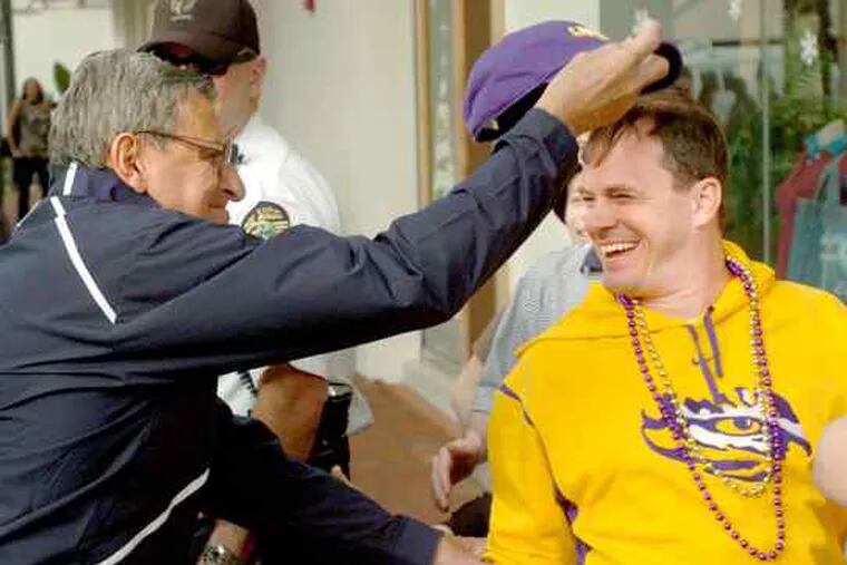 Penn State coach Joe Paterno playfully grabs the hat of LSU fan Shannon Nunez after a team pep rally in Orlando, Fla.