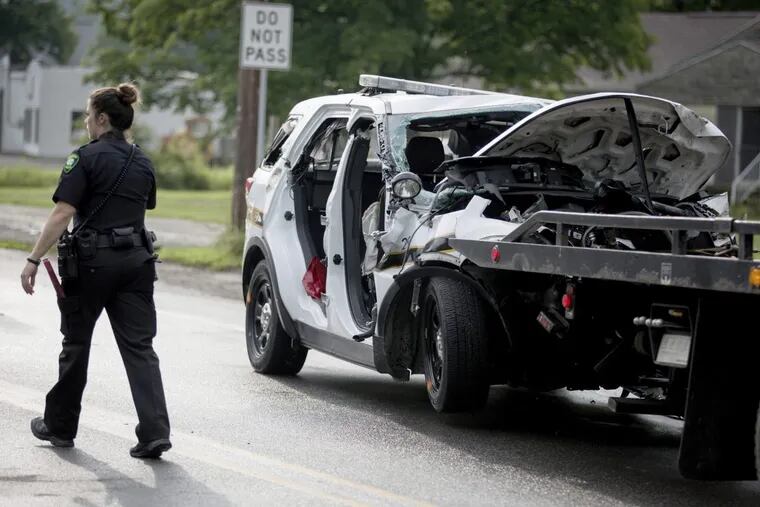 An officer walks by the wreckage of a Pennsylvania State Trooper vehicle at the scene of a fatal crash on State Route 711 on Friday, July 14, 2017 in Ligonier Township.