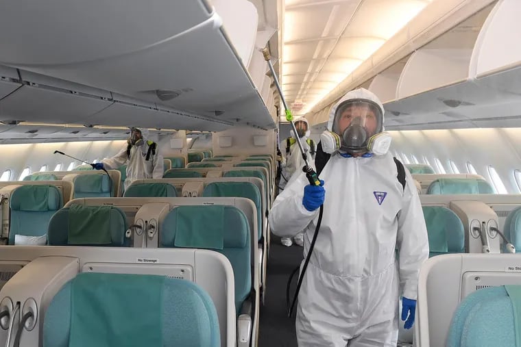 Workers wearing protective suits spraying disinfectant inside an airplane as a precaution against the coronavirus at the Incheon International Airport in Incheon, South Korea, in March.