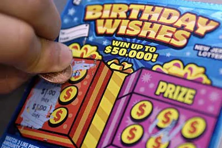 A customer scratches off a "Birthday Wishes" NJ Lottery ticket on Tuesday. The tickets are still being sold even though the top prize of $50,000 has already been won. (Tom Gralish/Inquirer)