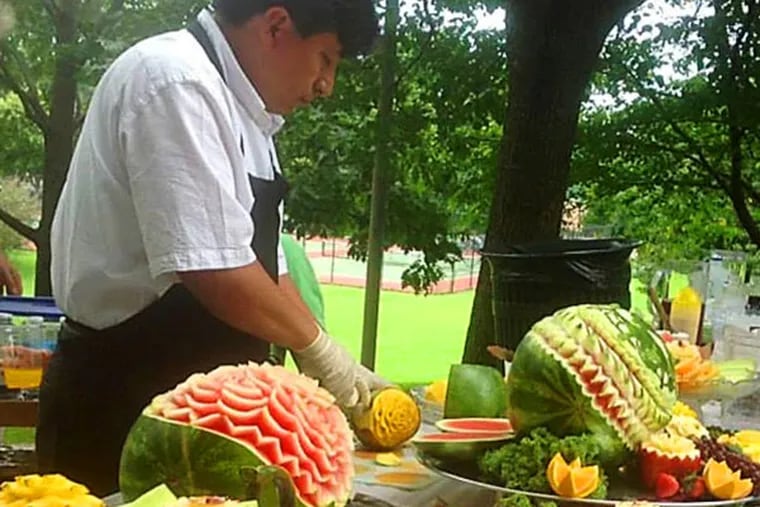 Roy Torres carves watermelons and other fruits at CARE Veggie Fest 2013.