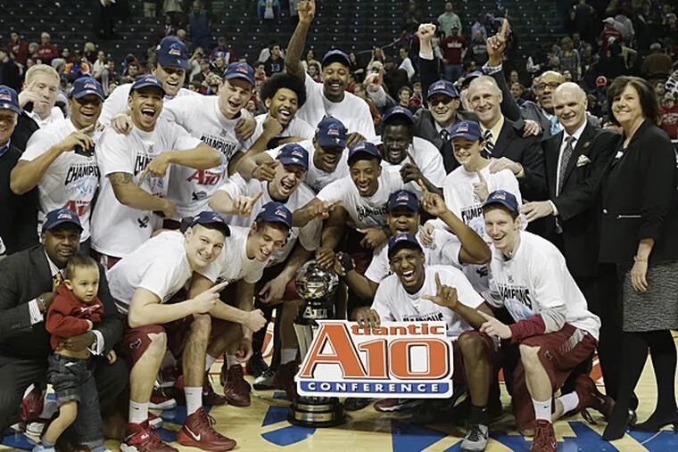 Saint Joseph's players, along with supporters and officials, pose with the championship trophy after beating VCU in the title game of the Atlantic 10 Conference tournament. (Seth Wenig/AP)