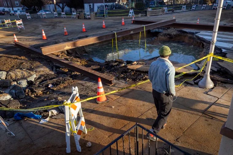 Ahmed Addy, resident of Kingsessing neighborhood walks past the large hole in middle of 56th and Springfield a day after a large water main break.