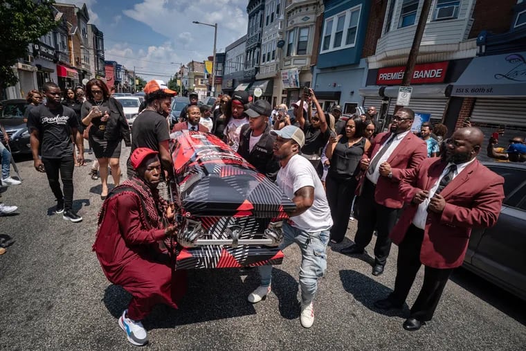 Pallbearers carry the casket of Sircarr Johnson Jr. down 60th Street in Philadelphia on July 17. They walked the casket carrying Johnson in front of the clothing store he owned.