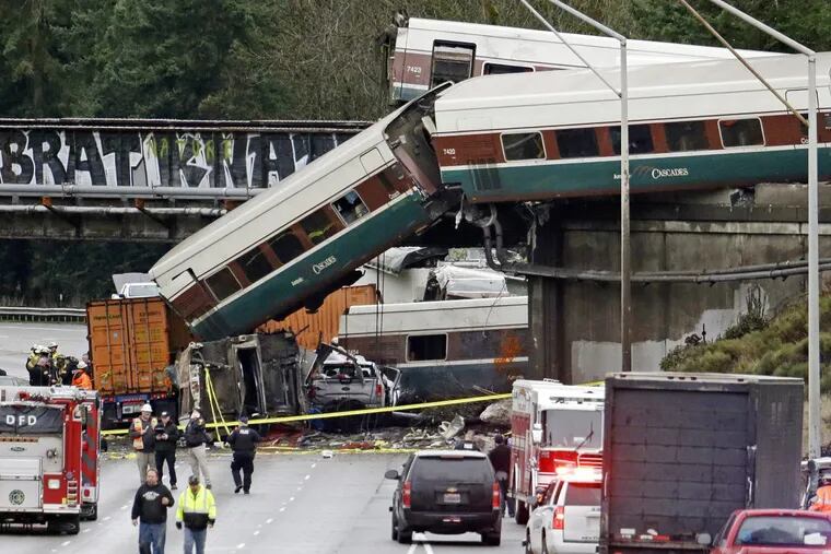 Cars from an Amtrak train lay spilled onto Interstate 5 below alongside smashed vehicles as some train cars remain on the tracks above Monday, Dec. 18, 2017, in DuPont, Wash.
