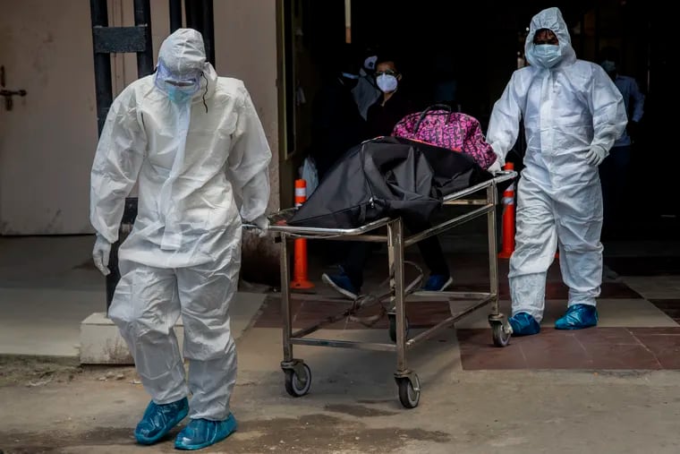 Health workers in protective suits shift the body of a COVID-19 victim at a government hospital May 24 in Gauhati, India. The nation has lost more than 300,000 people to the coronavirus, illustrating that the pandemic is far from over.