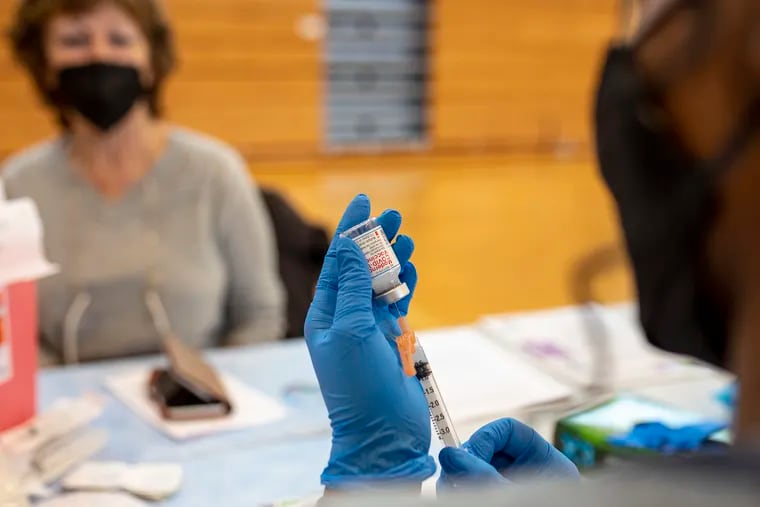 Health worker Yvonne Day prepares the shot to be given to nurse Linda Giangiordano in the gym at Lincoln High School Philadelphia on Friday. About 331 nurses were scheduled to be vaccinated at the clinic, set up by Philadelphia's health department and school district.