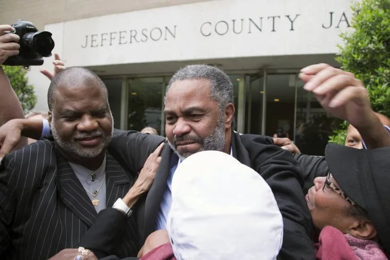 Friend Lester Bailey, left, and others greet Anthony Ray Hinton, center, as Hinton leaves the Jefferson County jail, Friday, April 3, 2015, in Birmingham, Ala. Hinton spent nearly 30 years on Alabama's death row, and was set free Friday after prosecutors told a judge they won't re-try him for the 1985 slayings of two fast-food managers. (AP Photo/ Hal Yeager)