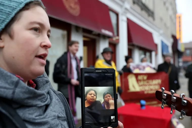 Gina Engst holds a digital tablet so Carmela Apolonio-Hernandez (left, on the screen) and Suyapa Reyes, both in church sanctuary at the time, could be a part of a rally outside the office of Congressman Dwight Evans in February. Evans' work helped to free Reyes and her children from sanctuary in March. Hernandez has spent more than two years in sanctuary.