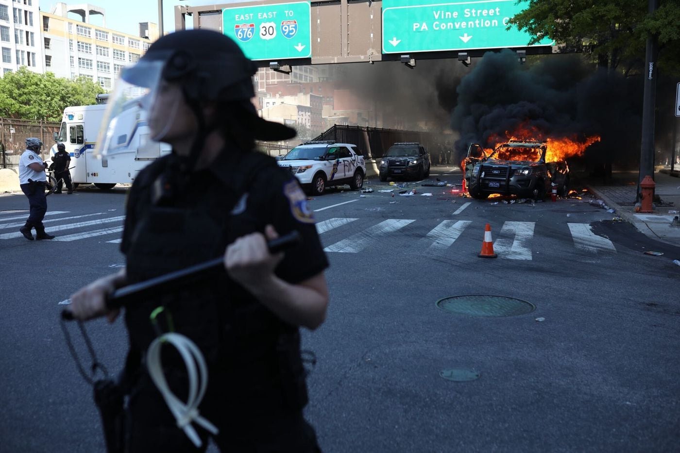 Philadelphia police push back protesters from a burning squad car before it blows up near the intersection of Broad and Vine Streets on May, 30, 2020.