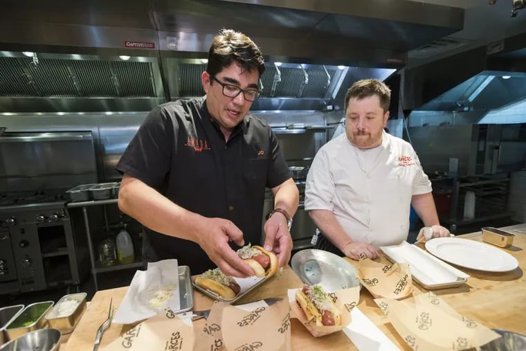Jose Garces (left) cooks with Gregg Ciprioni, vice president of culinary operations, in the test kitchen at 2401 Walnut St.