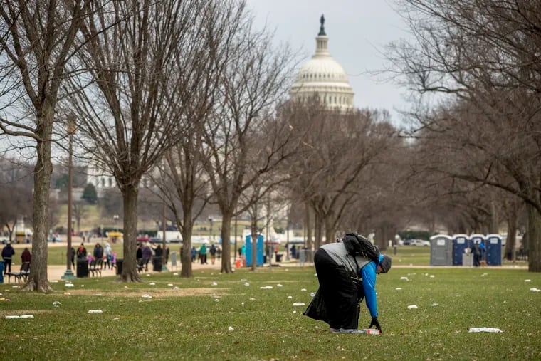 The Capitol building is visible as a man who declined to give his name picks up garbage during a partial government shutdown on the National Mall in Washington, Tuesday, Dec. 25, 2018.