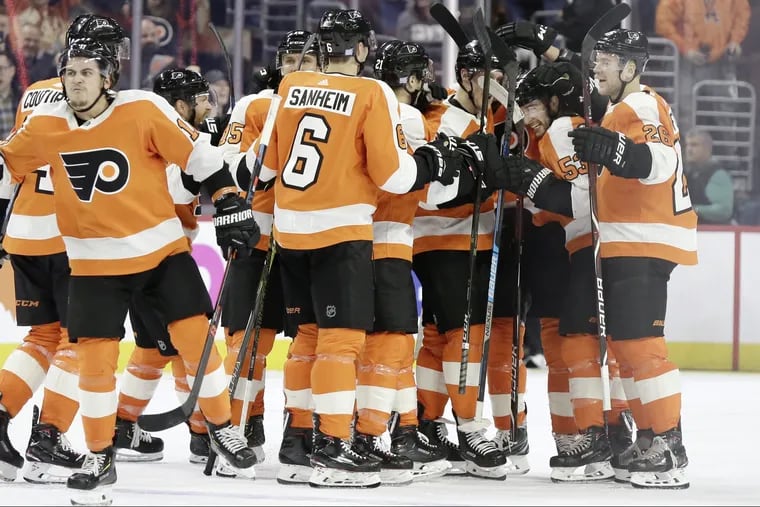 Shayne Gostisbehere (second from right) is mobbed by teammates after he scored in overtime during the Flyers' 5-4 comeback win Thursday over Arizona.