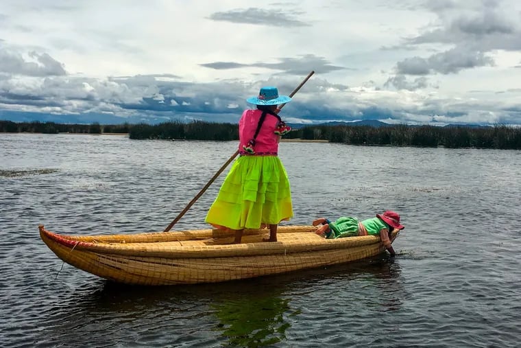 A young woman poles through the shallow waters of Lake Titicaca in Peru.  Uros Titino, one of the lake's famed floating islands, is home to the Uros, who live close to the shoreline where the reeds grow — their huts and boats are substantially made from reeds — and the lake is no more than 10 feet deep.