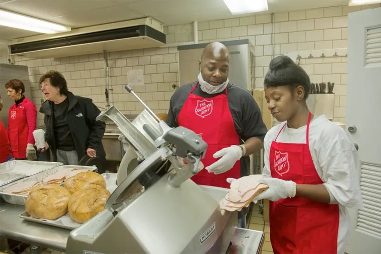 Arlene Olson, Program Director for the Soup's On program (left) gives instructions to volunteers and program participants while Soup's On Prep Cooks DuVal Everett (center) and Ashley Fulford slice turkey for Thanksgiving dinner packages for the needy at the Salvation Army in West Philadelphia.