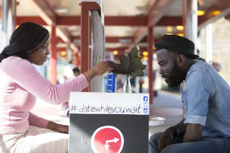 Thomas Knox, creator of Date While you Wait, plays Connect Four with ChiChi Nwadiogbu at the University City SEPTA Regional Rail station. Knox sets up a table with board games and brings it to communities where he would like to connect with people.