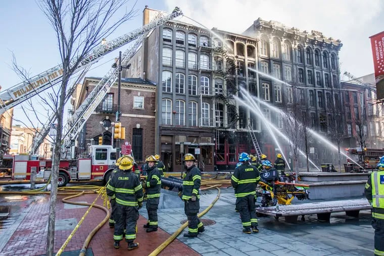 Philadelphia Firefighters watch as water is poured onto the 200 block of Chestnut Street in February 2018. City Council is considering legislation that would require sprinkler systems in more apartment buildings.