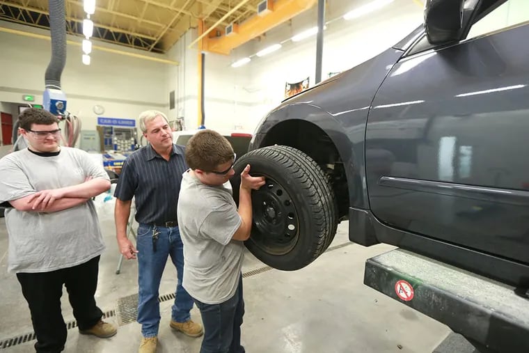 David Sandy, 19, watches as Adam Yost, 19, lifts a wheel on a 2008 Nissan Ultima they are rehabbing with teacher Mark Serfass at the Brandywine Campus of TCHS in Downingtown Tuesday October 14, 2014. ( DAVID SWANSON / Staff Photographer )