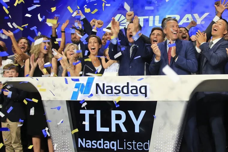 FILE- In this July 19, 2018, file photo Brendan Kennedy, third from right in front, CEO and founder of British Columbia-based Tilray Inc., a major Canadian marijuana grower, leads cheers as confetti falls to celebrate his company's IPO (TLRY) at Nasdaq in New York. Investors are craving marijuana stocks as Canada prepares to legalize pot next month, leading to giant gains for Canada-based companies listed on U.S. exchanges. (AP Photo/Bebeto Matthews, File)