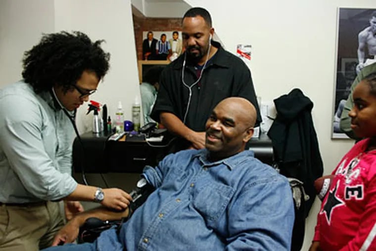 Medical student Kenji Taylor checks Jim Brown's blood pressure as Philly Cuts owner Darryl Thomas looks on. The students visit a shop every week or two. (ASHLEE ESPINAL / Staff Photographer)