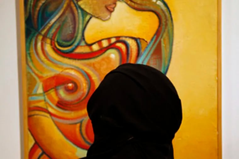 A woman regards an abstract portrait at the French Embassy in Riyadh, Saudi Arabia.
