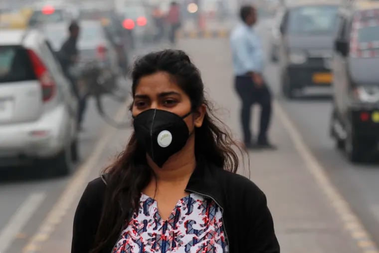 A commuter walks wearing a pollution mask amidst thick layer of smog in New Delhi, India, Thursday, Nov. 14, 2019. Schools in India's capital have been shut for Thursday and Friday after air quality plunged to a severe category for the third consecutive day, enveloping New Delhi in a thick gray haze of noxious air. (AP Photo/Manish Swarup)