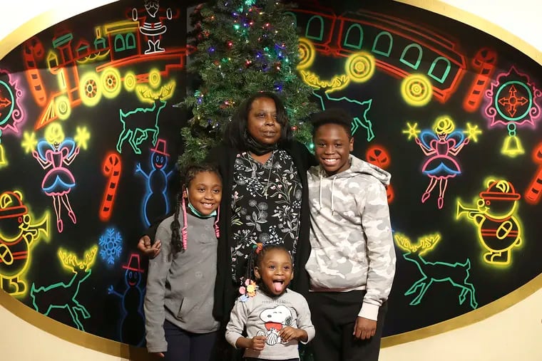 Arlene Watkins with her son, Elijah, and daughters Joy (left) and Ebony on Friday at the Dickens Village in the Center City Macy's. “God gave us our hearts’ desire,” she said. “He just did it on His time.”