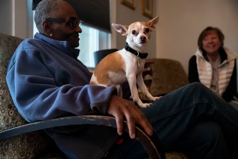 Milton Young sits with his dog, Tray, as Sam's Hope volunteer Leslie Woods sits nearby at his home in the Tacony neighborhood.