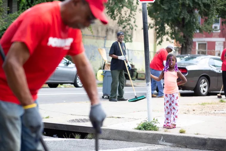 Zuri Johnson, 5, watches as members of the Black Male Community Council of Philadelphia clean up trash on the 2200 block of North Gratz St. in North Philadelphia.