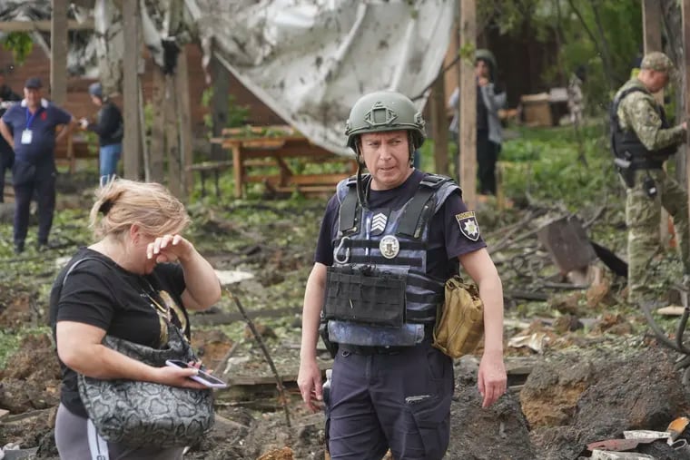 A woman cries as police officers inspect the site of the Russian missile attack that hit a recreation area, killing five people and injuring 16, on the outskirts of Kharkiv, Ukraine, on May 19.