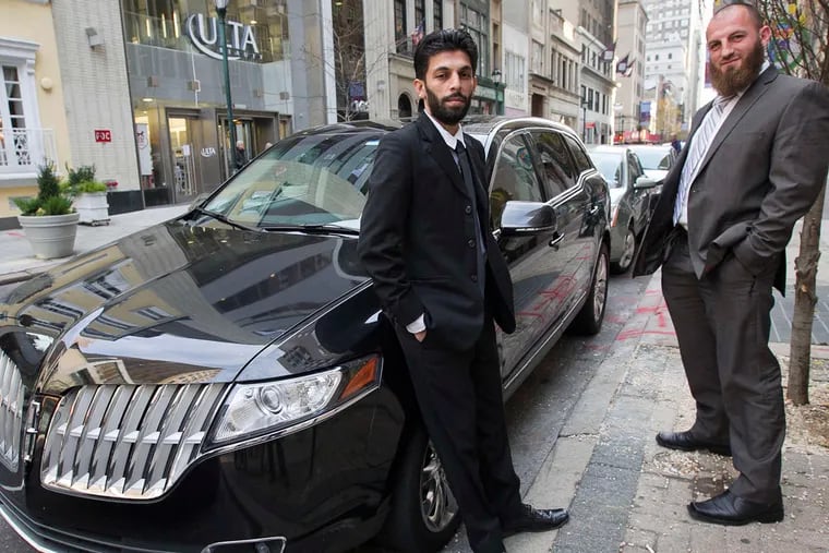 UberBlack drivers Ali Razak (left) and Kenan Sabani stand next to a vehicle along Walnut Street near 17th Street in Center City.