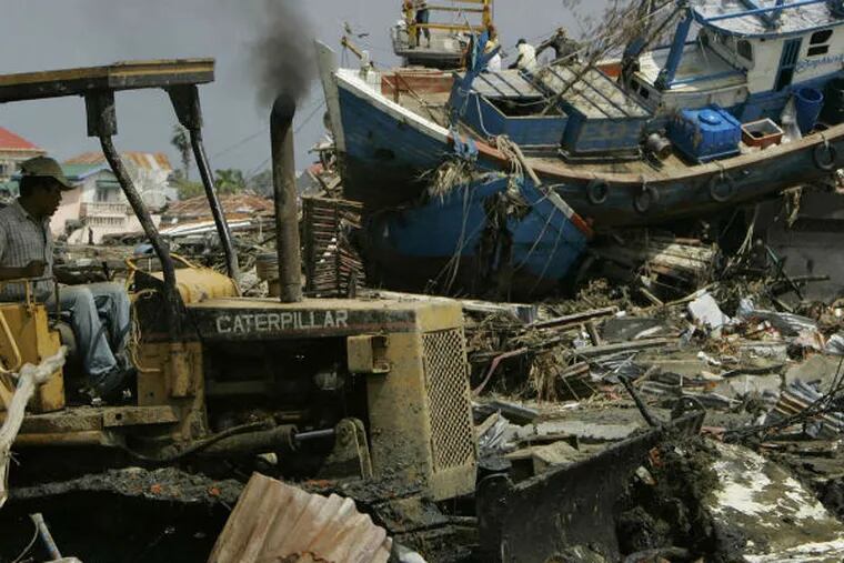 Weeks after the Dec. 26, 2004, tsunami, a bulldozer cleared rubble in front of a ship swept ashore in Indonesia. PETER DEJONG / Associated Press