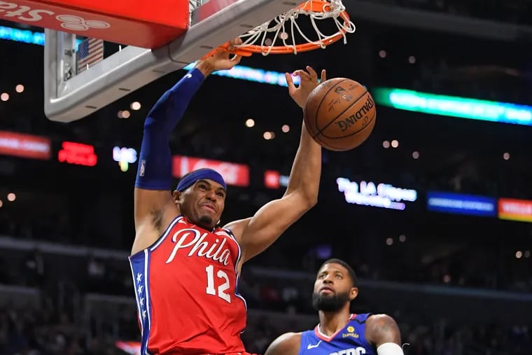 Sixers forward Tobias Harris dunks as Clippers guard Paul George looks on.