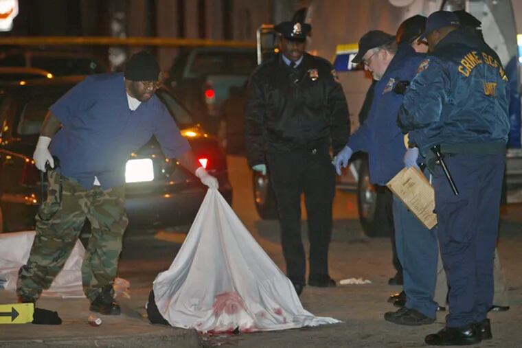 Police and medical examiners peer at one of two shooting victims in Germantown Thursday night.