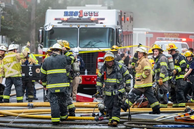 Philadelphia Fire Department personnel gather on the scene of a fire in July 2022. The department announced this week that it will reopen three companies that were shuttered in 2009 as a cost-cutting measure.