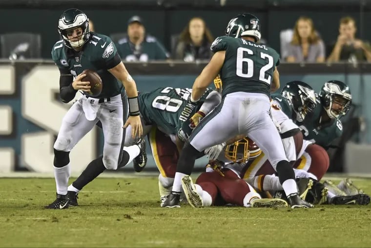 Eagles quarterback Carson Wentz escapes the scrum in the fourth quarter of the Eagles’ 34-24 win Redskins.