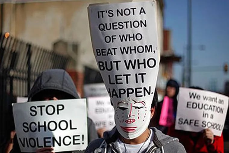 Asian students with their faces covered by signs march to a school board meeting Wednesday to express concerns about 30 assaults at South Philadelphia High School last week. They say the attacks were racially motivated. (AP Photo / Matt Rourke)