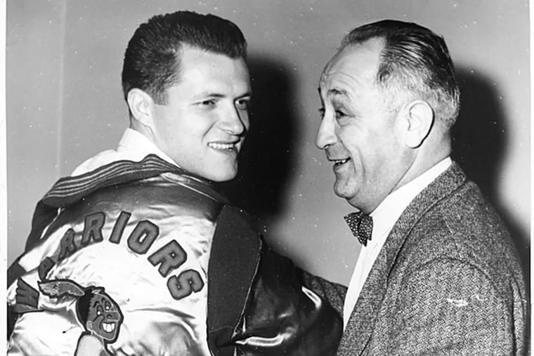 Tom Gola tries on the jacket of the Philadelphia Warriors basketball team held by coach Eddie Gottlieb. (Inquirer file photo)