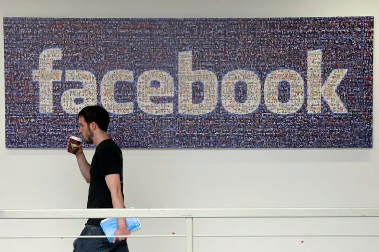 In this March 15, 2013, file photo, a man walks past a sign at Facebook headquarters in Menlo Park, Calif.  Facebook gave some companies more extensive access to users’ personal data than it has previously revealed, letting them read private messages or see the names of friends without consent, according to a New York Times report published Wednesday Dec. 19, 2018.