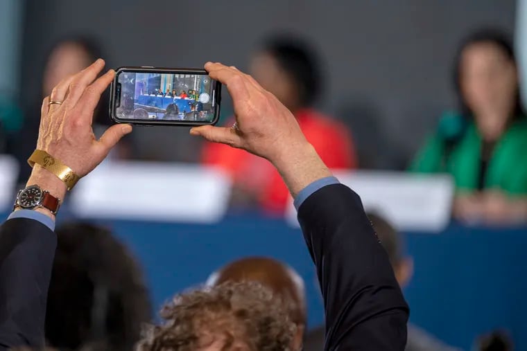 An audience member takes a photo of the candidates before the start of a televised mayoral forum on April 20, 2023.