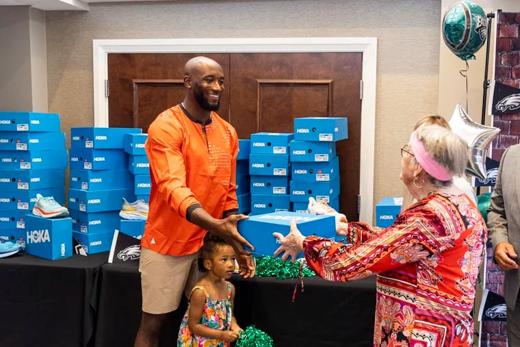 Eagles cornerback James Bradberry and his daughter Xena, 3, hand out pairs of sneakers to residents at the Simpson House in Philadelphia.